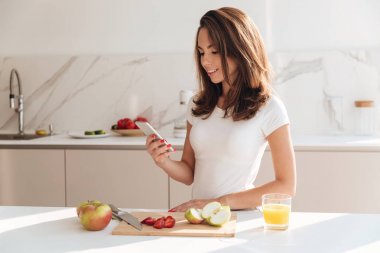 Genç kadın holding cep telefonu dururken gülümseyen