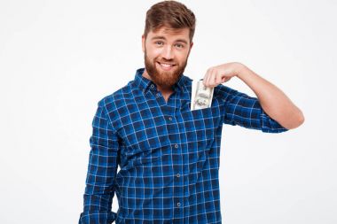 Kareli gömlek gülümseyen sakallı adam para cebine koyar.