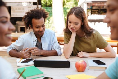 İki genç arkadaşlar açık havada oturma gülümseyen