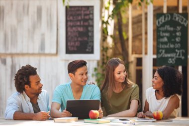 Masanın tarafından açık havada dört genç saçak