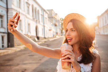 Genç ve güzel kadın açık havada telefonla selfie olun