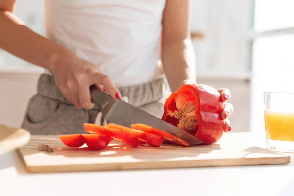 Крупный план портрета молодой женщины, нарезающей красный capsicum — стоковое фото