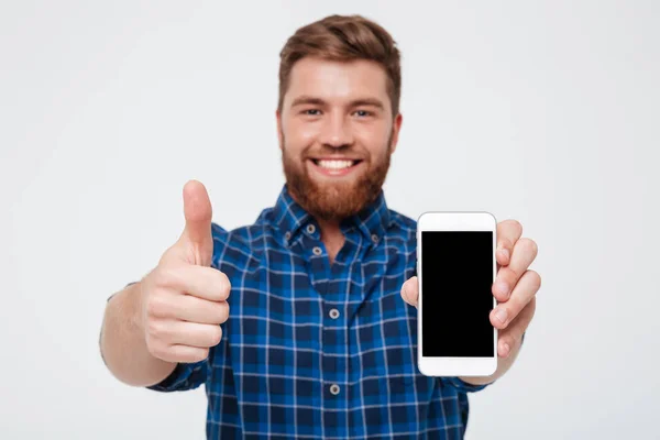 Sorrindo Homem barbudo em camisa quadriculada mostrando tela de smartphone em branco — Fotografia de Stock