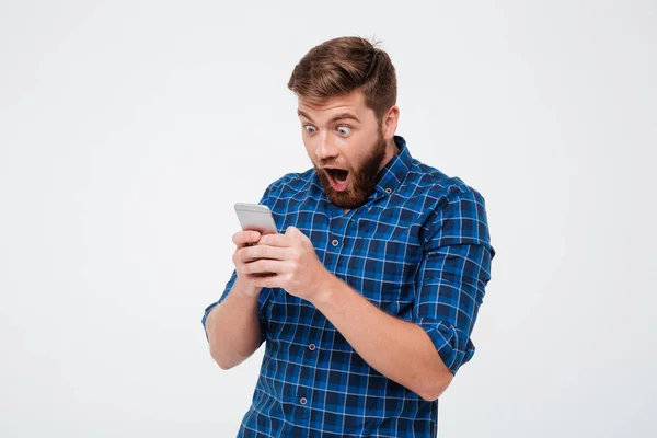 Chockad skäggig man i rutig skjorta skriva meddelande på smartphone — Stockfoto
