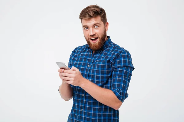 Surprised man in checkered shirt using smartphone — Stock Photo, Image