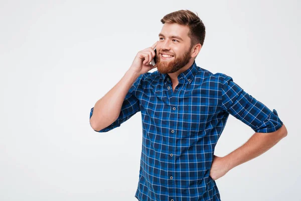 Homem barbudo sorridente em camisa quadriculada falando pelo smartphone — Fotografia de Stock