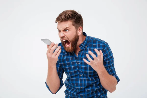 Бородатый мужчина в клетчатой рубашке кричит в смартфоне — стоковое фото