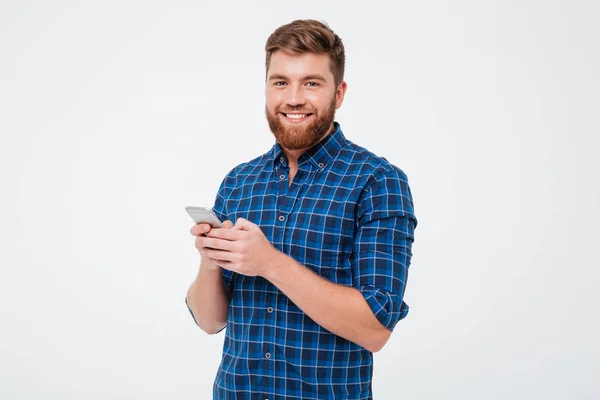 Hombre barbudo agradable con camisa a cuadros usando teléfono inteligente — Foto de Stock
