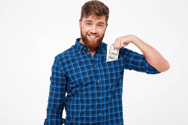 Kareli gömlek gülümseyen sakallı adam para cebine koyar.