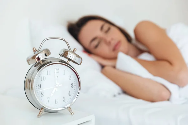 Retrato de cerca de un reloj despertador con mujer dormida — Foto de Stock