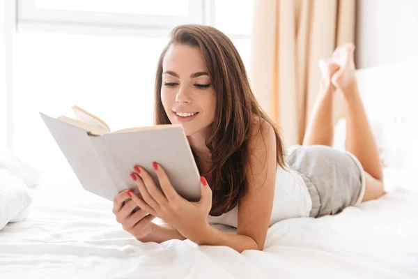 Улыбаясь, красивая женщина читает книгу во время укладки — стоковое фото