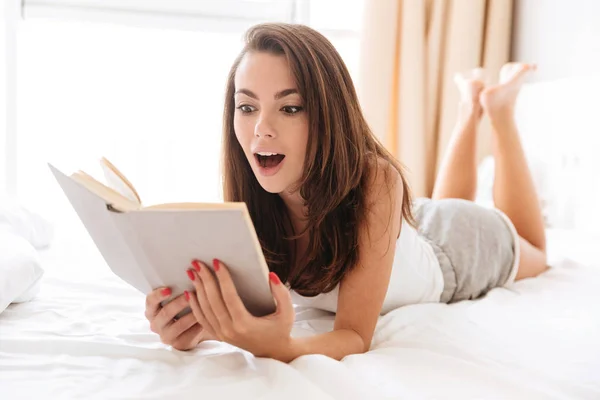 Uśmiechnięta dziewczyna zaskoczeni czytanie książki — Zdjęcie stockowe