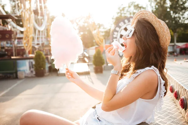 Вид збоку на дівчину в сонцезахисних окулярах, що їсть бавовняні цукерки — стокове фото