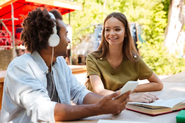 Zijaanzicht van twee gelukkige jonge vrienden zitten door tabel — Stockfoto