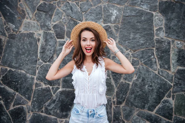 Fröhliche junge Frau steht über Mauer im Freien — Stockfoto