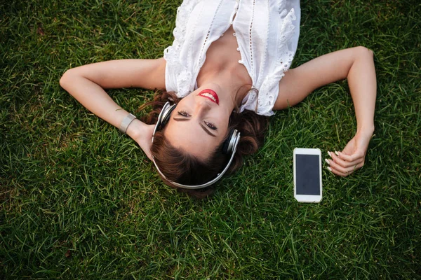 Szczęśliwa młoda kobieta leży na trawie, na zewnątrz. — Zdjęcie stockowe