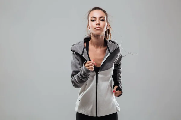 Corredor femenino serio en ropa de abrigo corriendo en el estudio — Foto de Stock