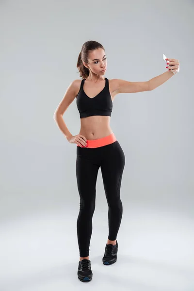 Pełna długość zdjęcie kobiety fitness pozowanie i podejmowania selfie — Zdjęcie stockowe