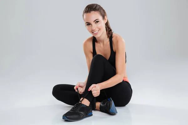 Gelukkig fitness vrouw zittend op de vloer en stropdas schoenveters — Stockfoto