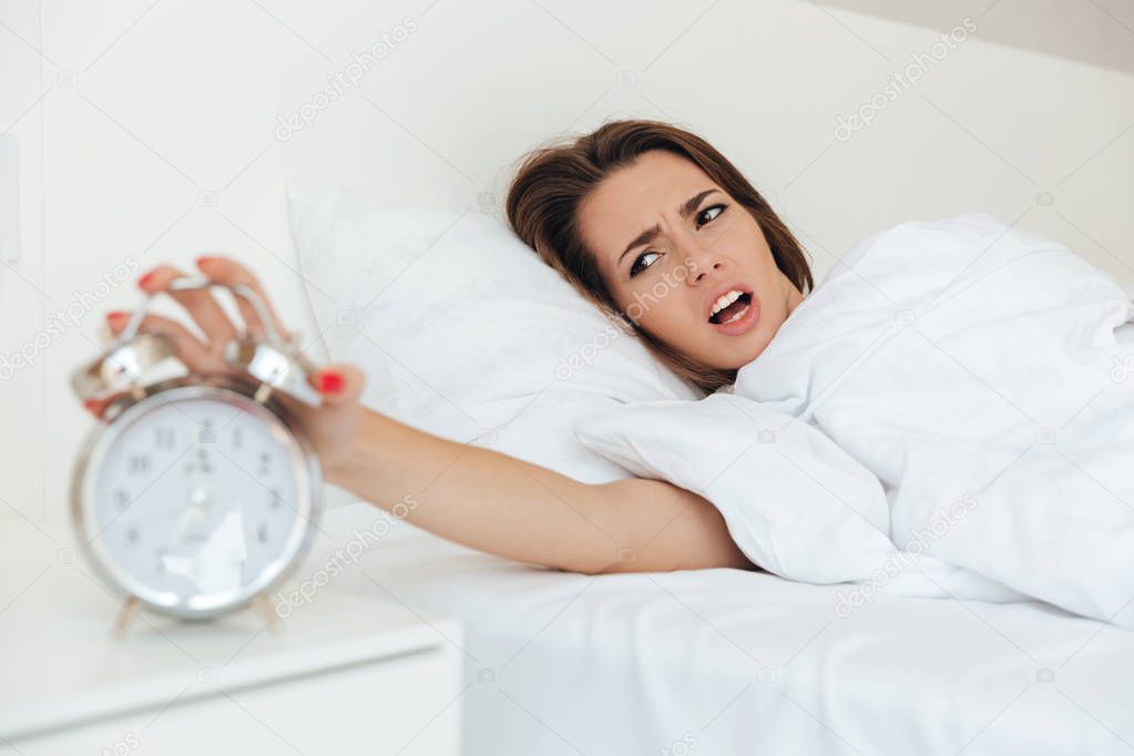 Annoyed young woman laying in bed