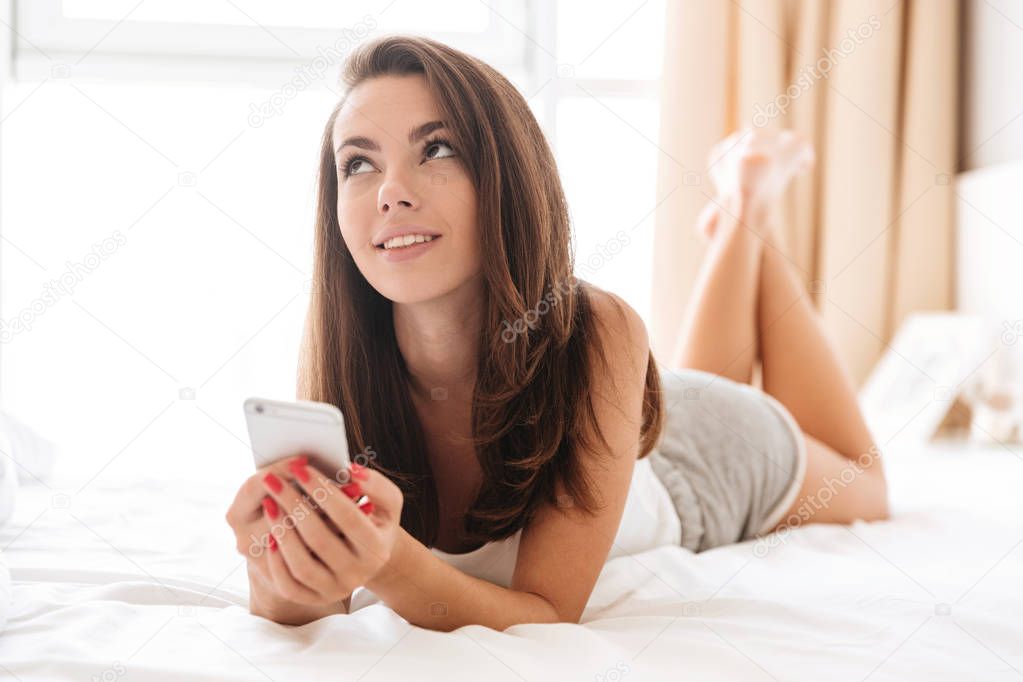 Close up portrait of pretty pensive woman holding mobile phone
