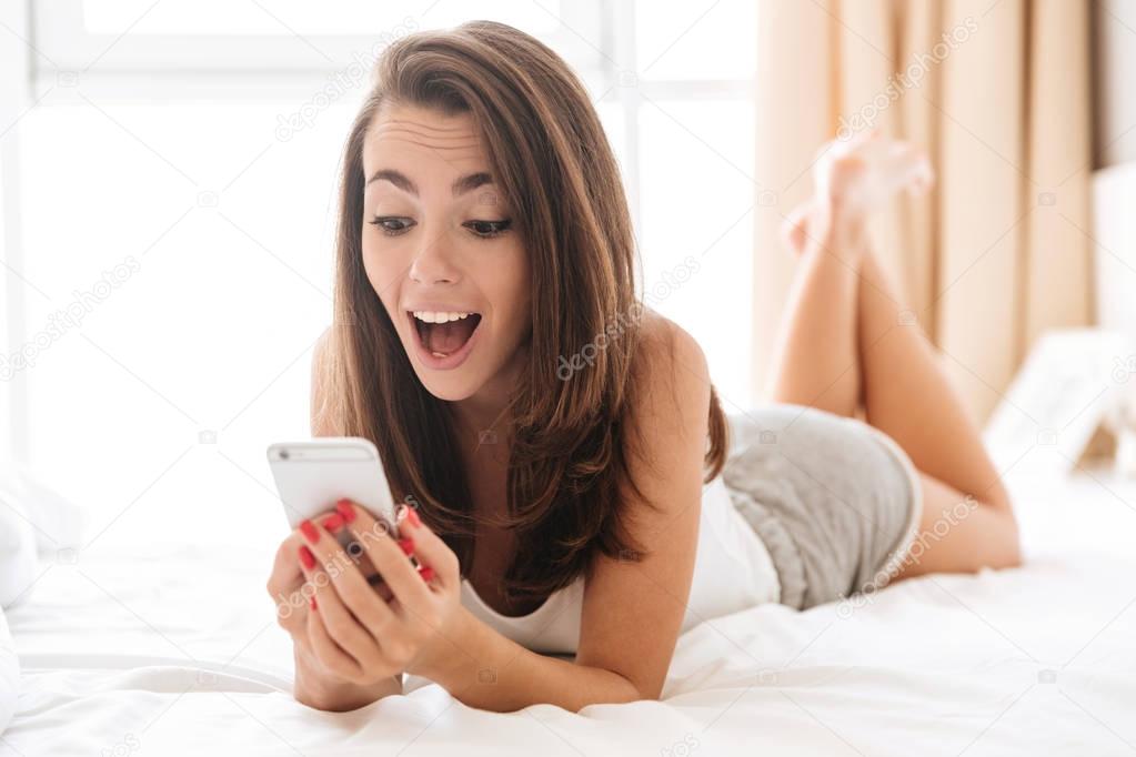 Close up portrait of happy excited woman using mobile phone