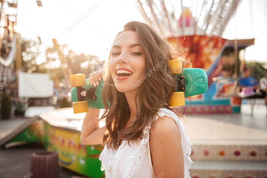 Smiling young woman holding skateboard outdoors