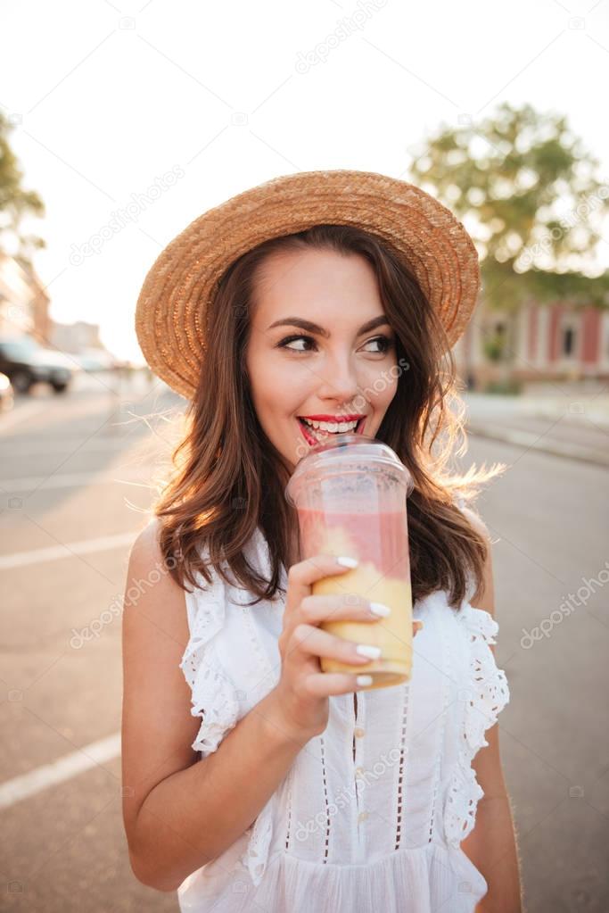 Beautiful young woman outdoors drinking juice