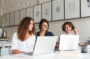 Üç genç mutlu kadın tarafından tablo çalışma