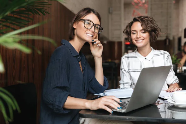İki kadın yöneticileri tarafından masanın gülümseyen yan görünüm