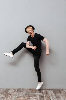 Beyaz adam gri duvardan yürüyerek gözlüklü