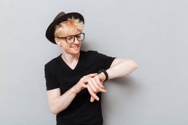 Saatini kullanarak gözlük takan adam.