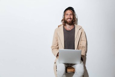 Dizüstü bilgisayar kullanan kamera bakacak mutlu hipster adam.