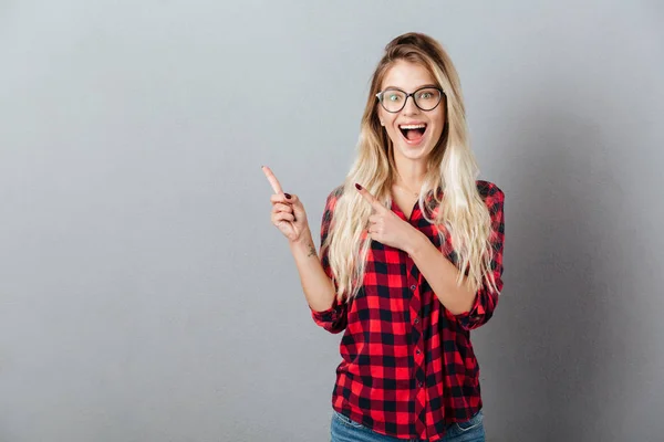 Mujer rubia joven apuntando al copyspace — Foto de Stock