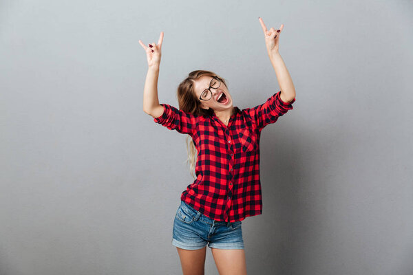 Amazing young blonde woman showing rock gesture.