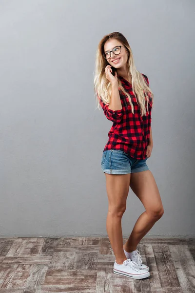 Neşeli genç sarışın kadın telefonla konuşuyor.