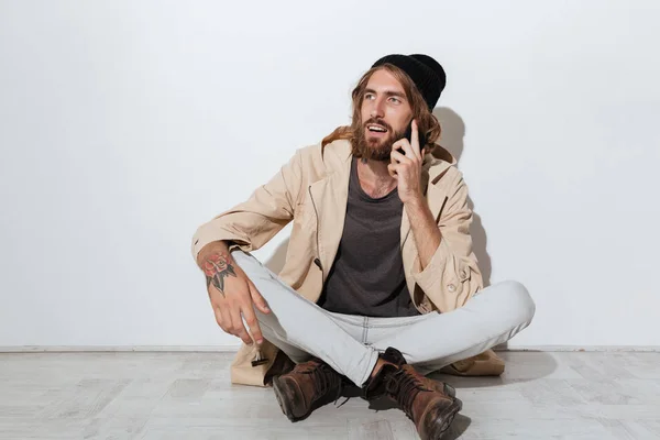 Hipster man die opzij vergadering geïsoleerd over muur — Stockfoto