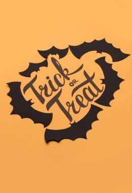 Logo Cadılar Bayramı ve turuncu zemin üzerine boyalı siyah yarasa