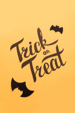 Logo Cadılar Bayramı ve turuncu zemin üzerine boyalı siyah yarasa