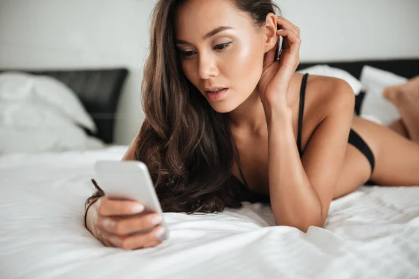 Ελκυστική γυναίκα της Ασίας σε σέξι εσώρουχα χρησιμοποιώντας το κινητό τηλέφωνο — Φωτογραφία Αρχείου