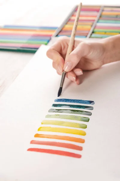 Künstler bemalt bunte Streifen mit Pinsel auf weißem Papier — Stockfoto