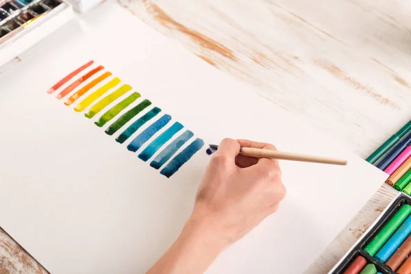 Künstler bemalt bunte Streifen mit Pinsel auf weißem Papier — Stockfoto