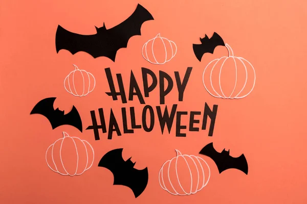 Hand written phrase Happy Halloween with pumpkins and bats near it