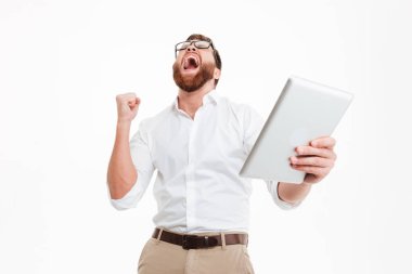 Mutlu genç sakallı adam tablet bilgisayar yapmak kazanan hareketini kullanarak.