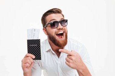 Pasaport ve bilet işaret ederken tutan adam mutlu genç sakallı.