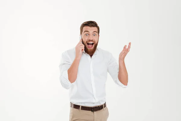 Веселый молодой бородатый эмоциональный мужчина разговаривает по телефону . — стоковое фото