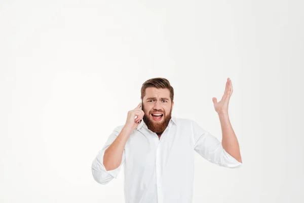 Angry young bearded emotional man talking by phone. — Stock Photo, Image