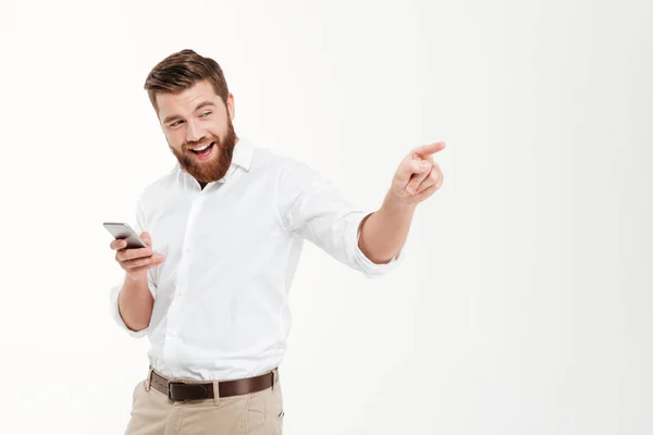 Bebaarde gelukkig man wijzen en chatten via de telefoon. — Stockfoto