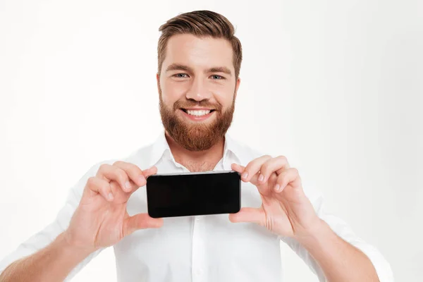 Cheerful young bearded emotional man showing display of phone. — Stock Photo, Image
