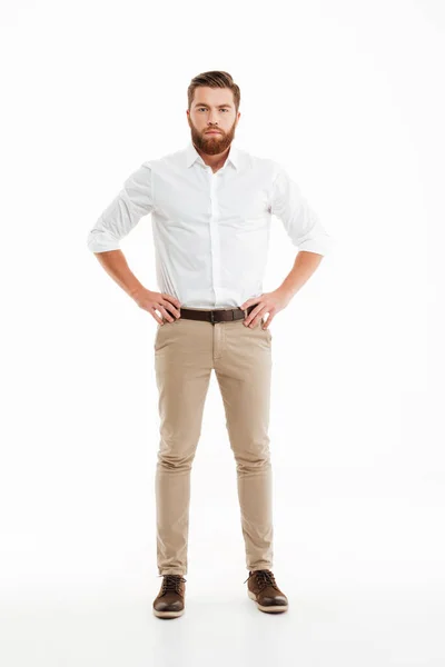 Ciddi genç sakallı adam beyaz duvardan ayakta — Stok fotoğraf
